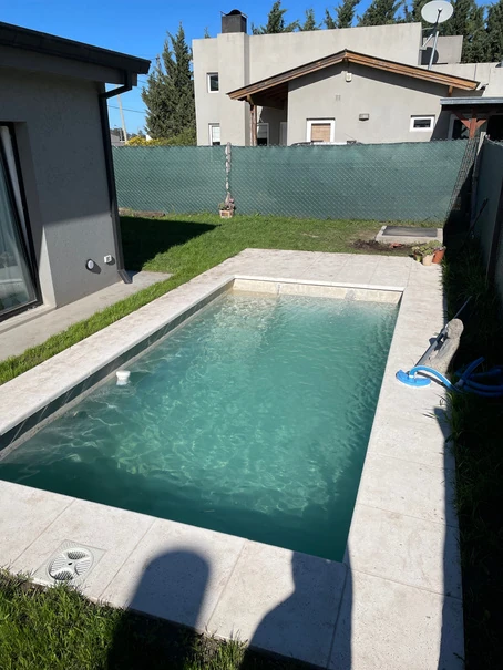 Piscina rectangular terminada, con césped y vereda atérmica