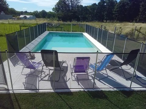 Piscina con cerramiento y sector exterior con reposeras