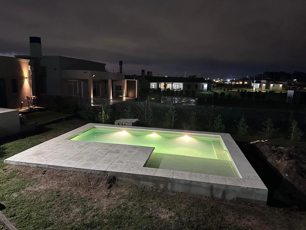 Piscina construida por Cepiscinas con iluminación subacuática encendida al atardecer